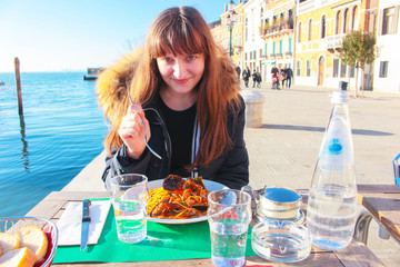 Girl dining seafood in an outdoor cafe at the Grand canal in Venice