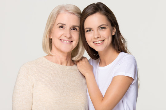 Smiling adult daughter and old mother bonding isolated on background