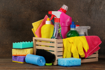 Bottles with cleansers and detergents in a box on a brown background. cleaning. cleaning products.