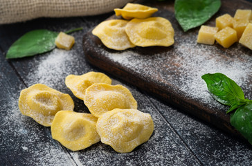 Fresh ravioli with cheese and Basil sprinkled with flour on wooden background on kitchen table, dark background