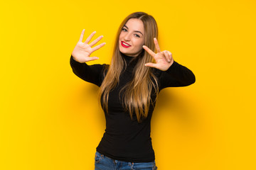 Young pretty woman over yellow background counting eight with fingers