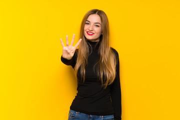 Young pretty woman over yellow background happy and counting four with fingers