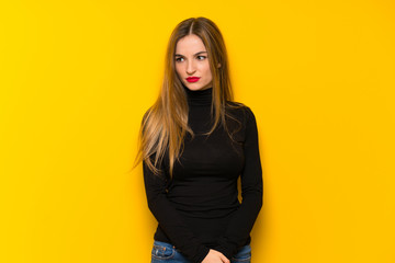 Young pretty woman over yellow background feeling upset