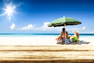 Desk of free space for your product. Beach landscape with people on towel. Ocean water and sun light