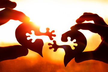 Two halves of the heart in the hands of people against the evening sky, sunset. love, relationships.