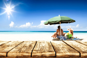 Desk of free space for your product. Beach landscape with people on towel. Ocean water and sun light