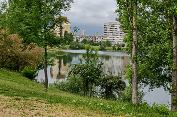 Obraz premium Spring panorama of a part of residential district neighborhood along a lake with green trees, shrubs and flowers, Drujba, Sofia, Bulgaria 