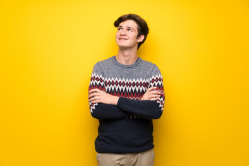 Fototapeta premium Teenager man over yellow wall looking up while smiling
