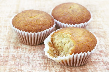 Close up group of banana cup cake bakery, some piece was bited, look delicious on wooden table background, vintage tone.