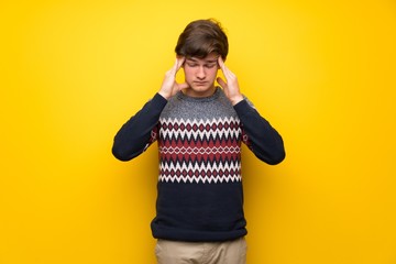 Teenager man over yellow wall with headache