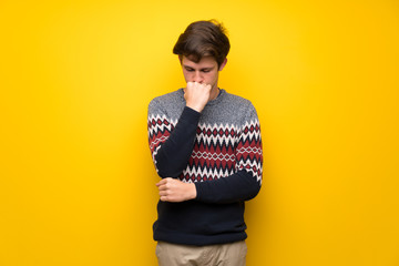 Teenager man over yellow wall having doubts