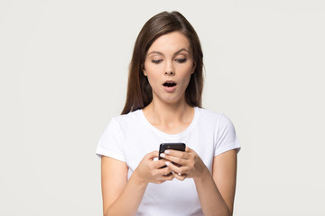 Fototapeta premium Shocked girl holding phone feeling stunned about unexpected mobile message