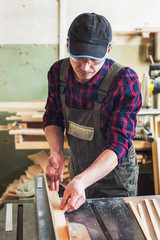 Carpenter worker cutting wooden board with circular saw. Profession, carpentry and woodwork concept.