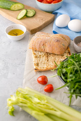 Preparing ciabatta sandwich with tuna, eggs and veggies