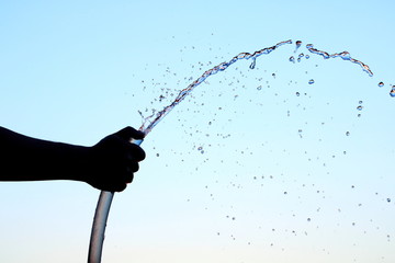 silhouette hand people use fingure close watering end of rubber water hose then water like spray on...