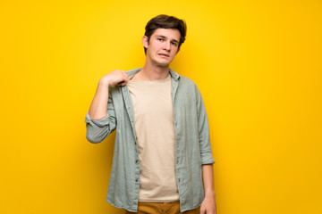 Teenager man over yellow wall with tired and sick expression