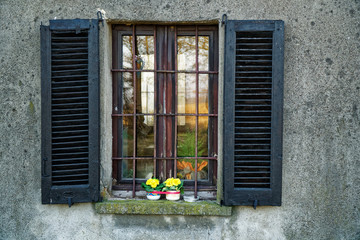 Fototapeta na wymiar Window in old vintage style with open wooden shutters and fresh flowers