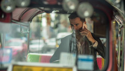 Caucasian Business Man Talking in a cell phone in Tuk Tuk, Chinatown Bangkok Thailand