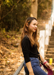 Women white skin lovely brown hair a small woman red lips wearing a black shirt wearing a blue gene woman stand  poses photography portrait which has both trees and water in the back in the park.