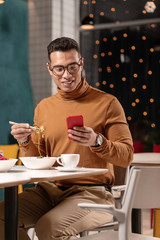 Girl sending photo to African American guy who having dinner at restaurant.