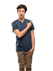 Teenager man surprised and pointing side over isolated white background