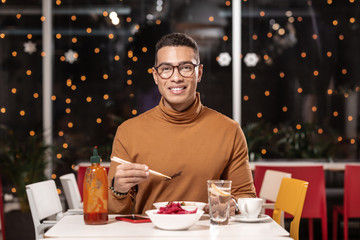 Customer sitting at the table and looking at the camera while eating meal.