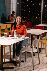 Girl laughing at the joke that showing on TV that standing in a cafe.