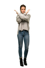 A full-length shot of a Blonde woman with turtleneck making NO gesture over isolated white...