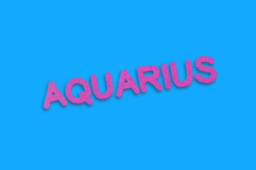 Word aquarius cut out of purple paper on blue table. Top view. Horoscope concept