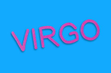 Word virgo cut out of purple paper on blue table. Top view. Horoscope concept