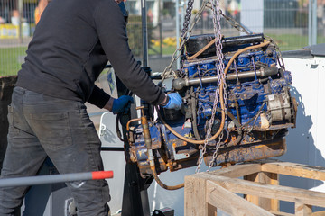 mechanic uses lifting equipment to remove engine block from boat