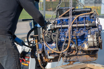 mechanic uses lifting equipment to remove engine block from boat