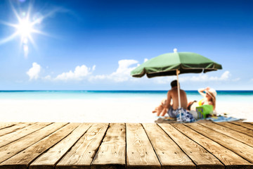 Desk of free space for your product. Beach landscape with people on towel. Ocean water and sun light