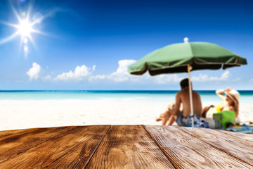 Desk of free space for your product. Beach landscape with people on towel. Ocean water and sun light