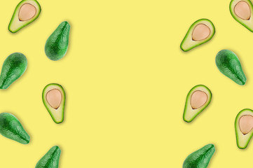 Scattered fresh wholes and halves of organic avocado with kernels on yellow table in kitchen or market. Top view. Cooking concept. Copy space for your text