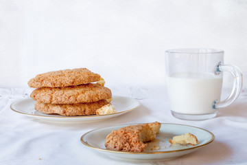 Traditional American chips cookies childhood breakfast snack with bite piece and milk glass on white table copyspace
