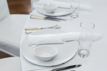 served table in the restaurant. clean white dishes layout on a white tablecloth