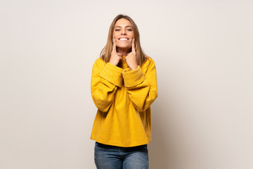 Woman with yellow sweater over isolated wall smiling with a happy and pleasant expression