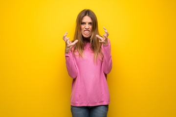 Woman with pink sweater over yellow wall frustrated by a bad situation