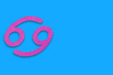 Symbol of astrological sign cancer cut out of purple paper on blue table. Top view. Horoscope concept. Copy space for your text