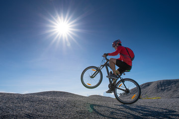 Fototapeta na wymiar Cyclist riding mountain bike on the rocky trail at sunset. Extreme mountain bike sport athlete man riding outdoors lifestyle trail. 