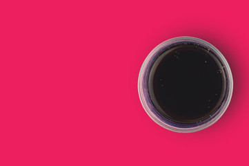 One full glass of aerated cola black color with bubbles on red table in cuisine. Copy space for your text. Top view. Rest concept