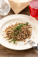 cooked buckwheat on white plate with berry juice on wooden table