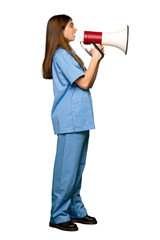 Full-length shot of Young nurse shouting through a megaphone on isolated white background