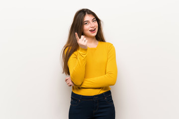 Young woman with yellow sweater points finger at you with a confident expression