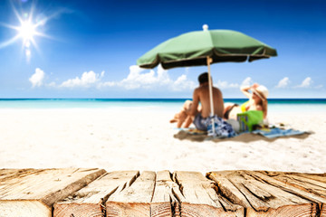 Desk of free space for your product. Beach landscape with people on towel. Ocean water and sun light