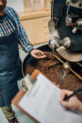 Barista is having the roast of his coffee beans quality checked by the manager. Roasted coffee beans being graded