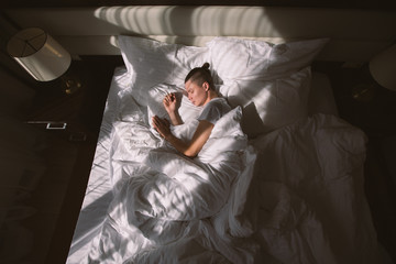 Top view - a young male tourist is sleeping in his bed under the rays of the morning sun. The...