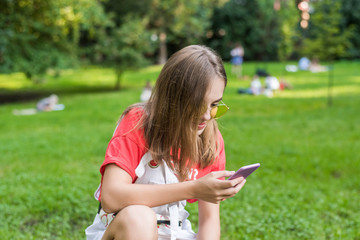 Student teenage girl portrait holding smartphone. in park smiling happy going back to school. Chat with friends online, social networks, virtual life