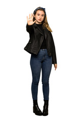 A full-length shot of a Teenager girl with leather jacket making stop gesture denying a situation that thinks wrong on isolated white background